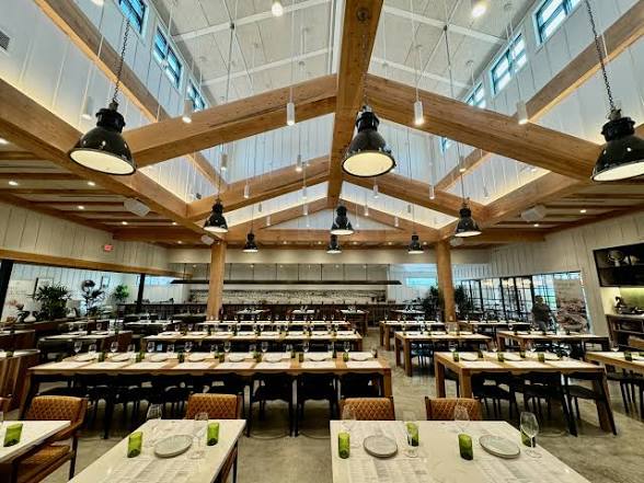 The light, airy Sixty Vines dining room with vaulted wood beams and long communal tables