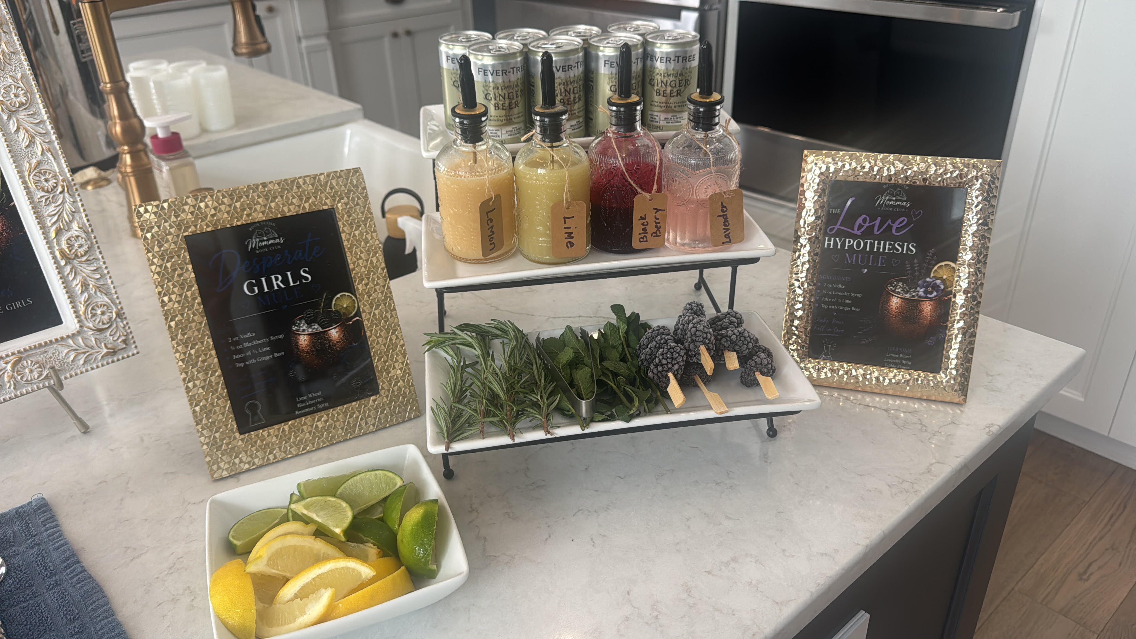 Mule bar ingredients including lemon, lime, blackberry, and lavender syrups, fresh mint, rosemary, and blackberries