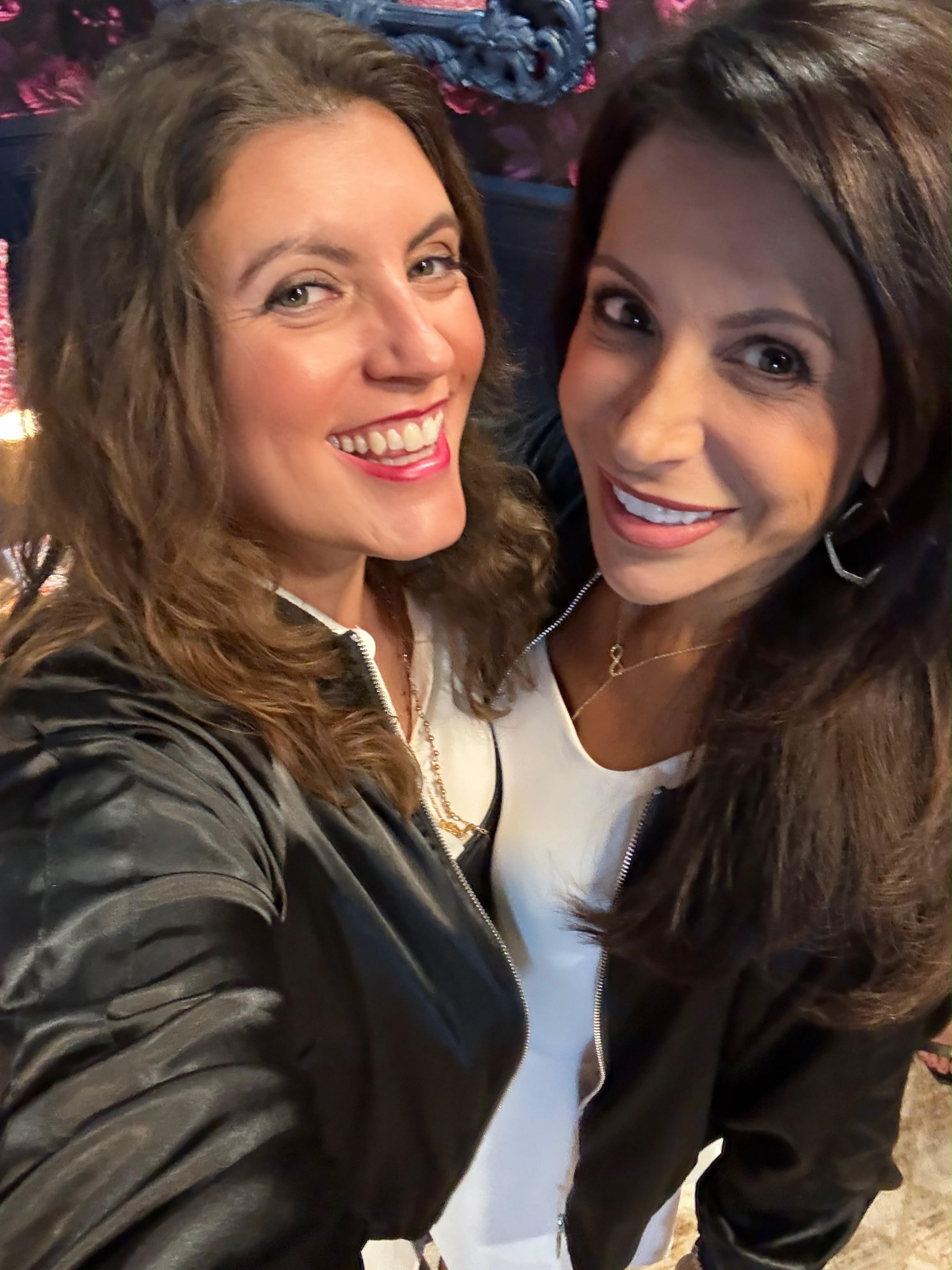 Two Book Fetish Momma members smiling in their white dresses and black bomber jackets